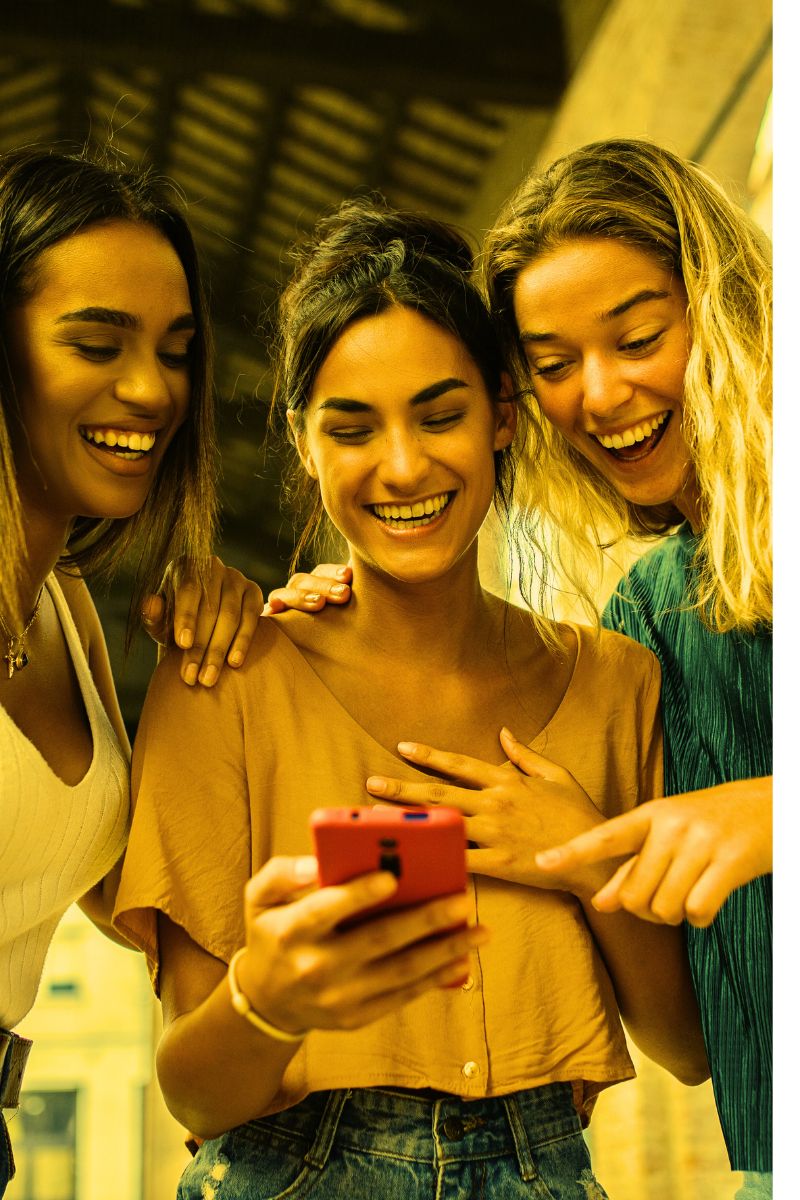 three friends looking at a phone - AdobeStock-517526905