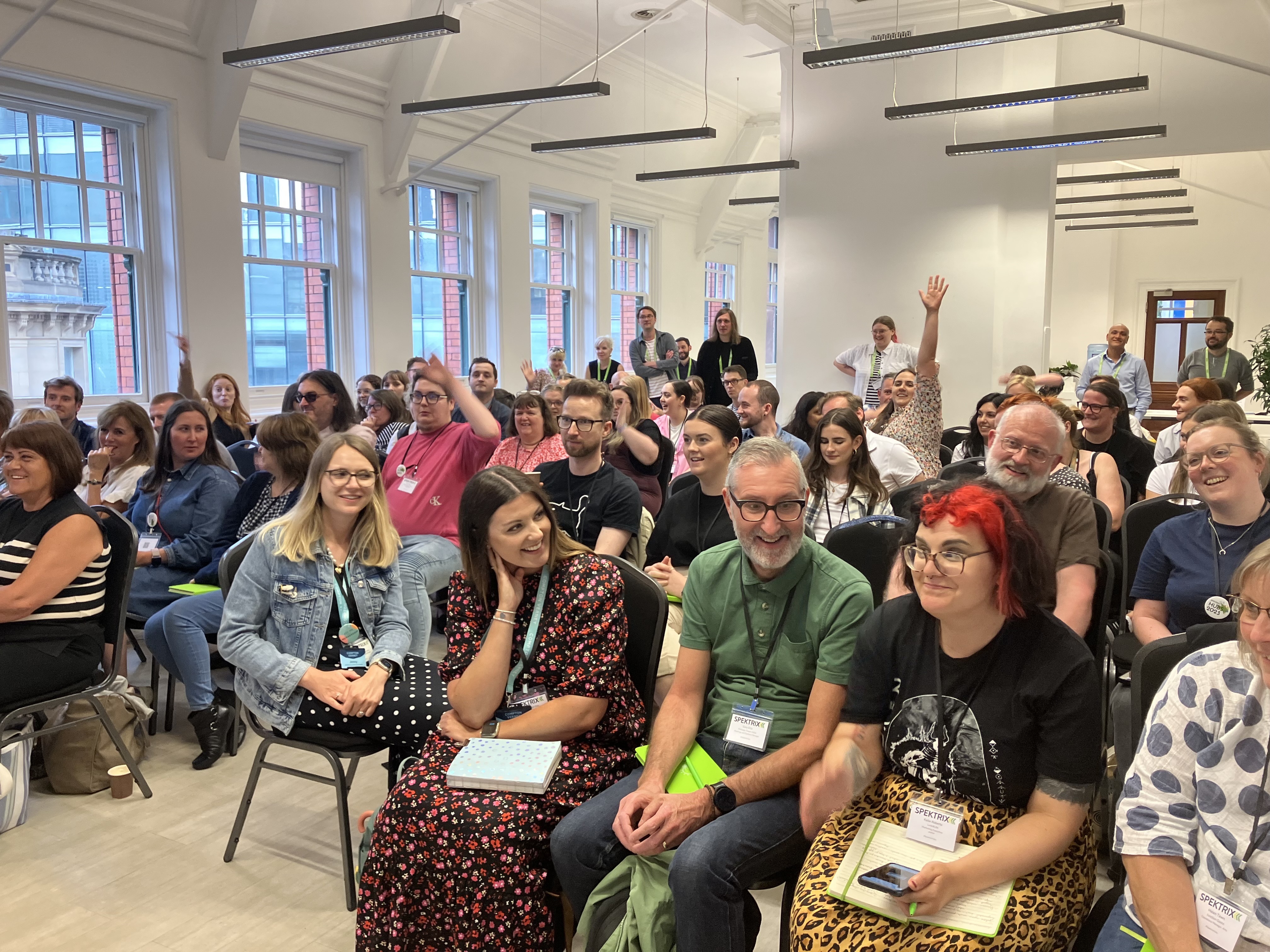 Attendees discuss a question and raise hands at Spektrix Hubs 2023 in Manchester. 