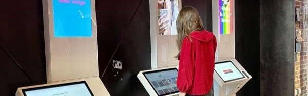 A person in a red jacked engages with kiosks at Storyhouse in Chester.